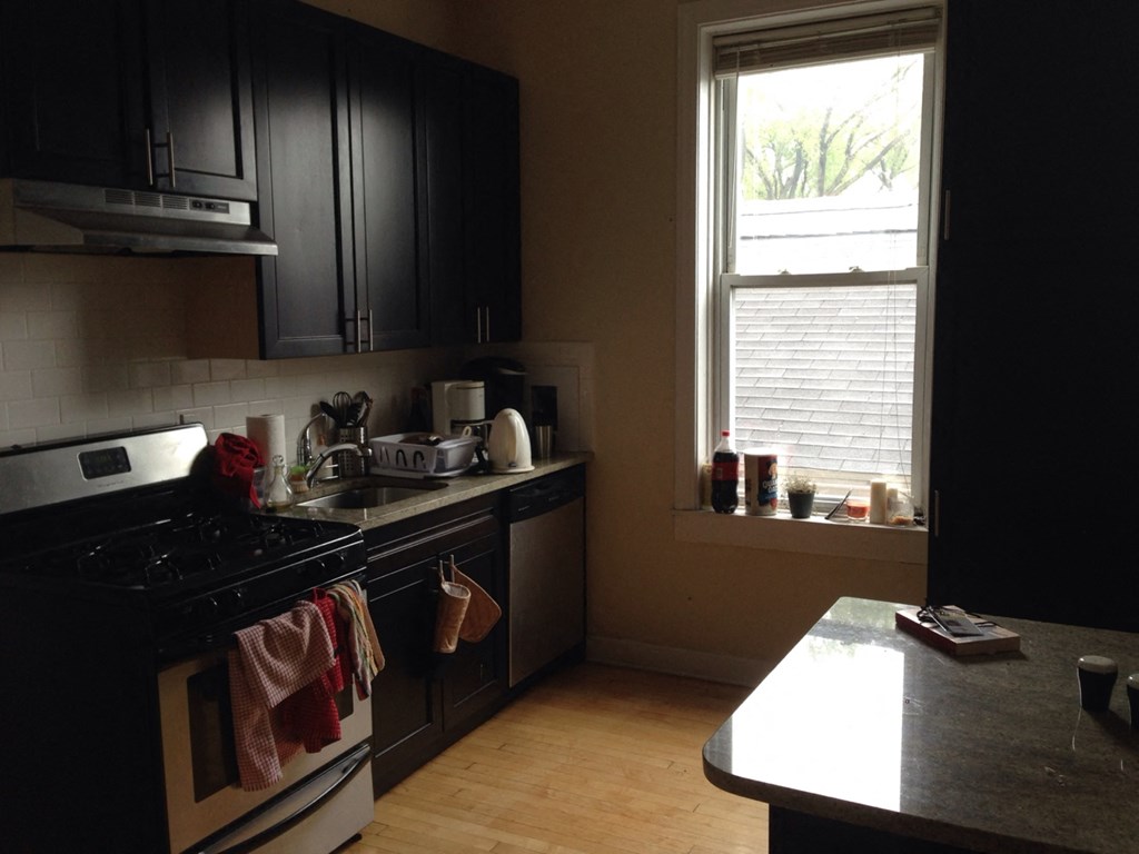 a kitchen with black cabinets and a stove and a window