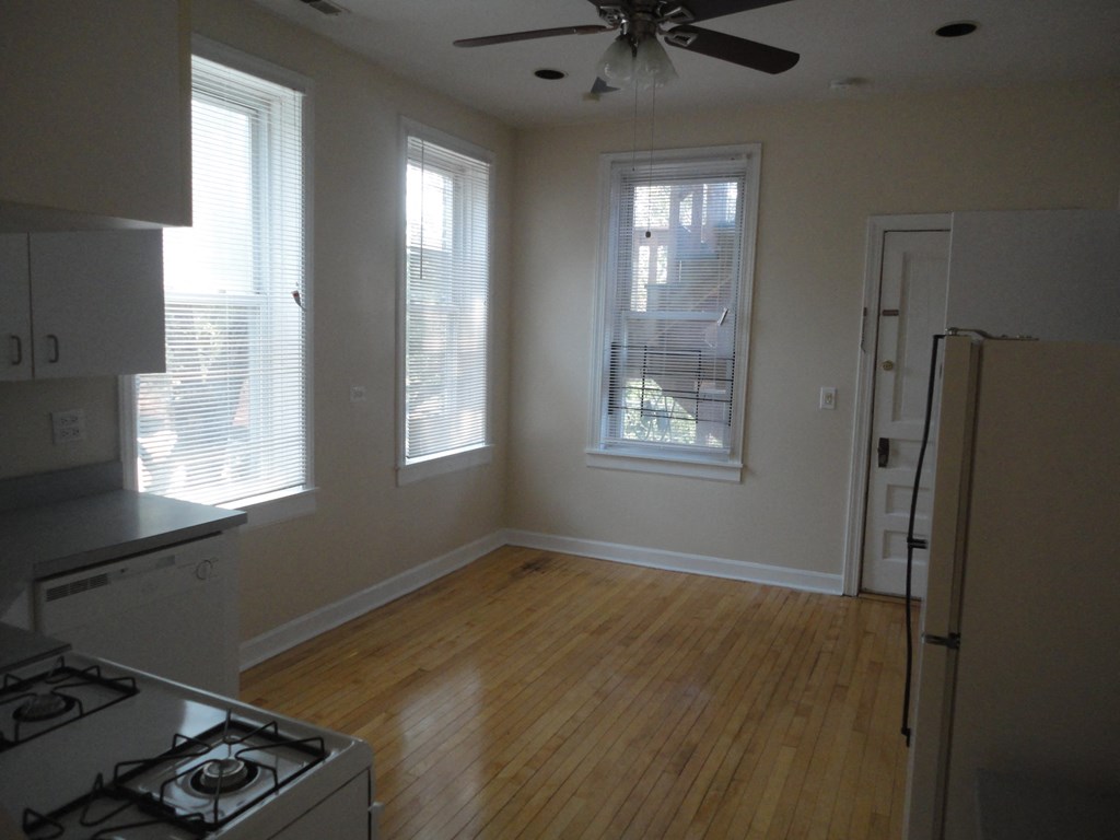 an empty kitchen with a wood floor and windows