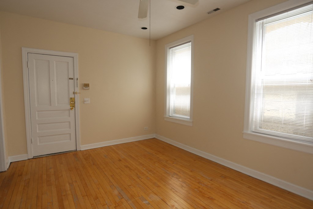 an empty room with a door and two windows