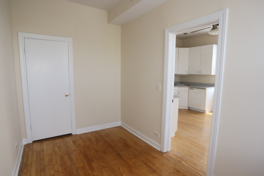an empty living room with a door to a kitchen