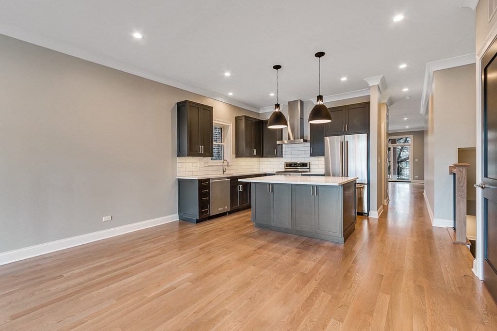 an open kitchen and living room with a large island and wood floors