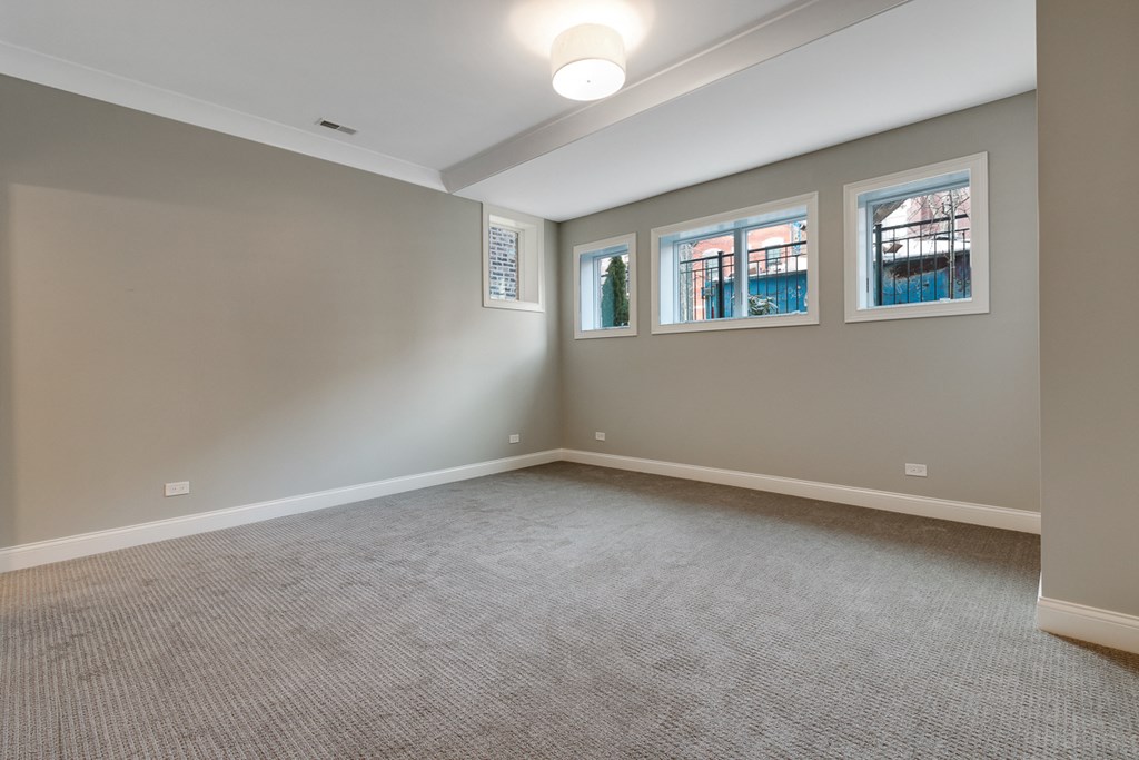 an empty room with carpet and three windows