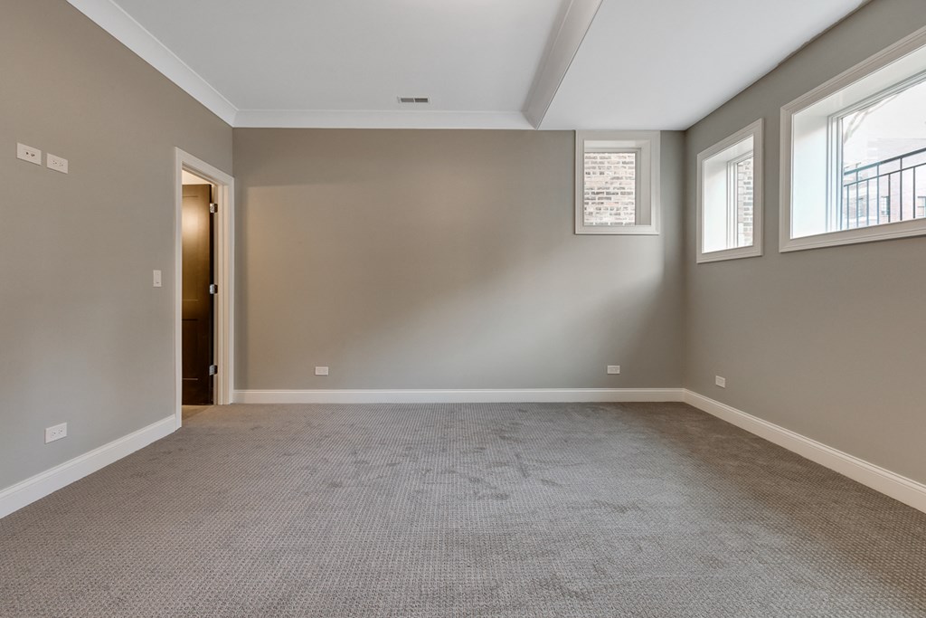 an empty living room with carpet and three windows