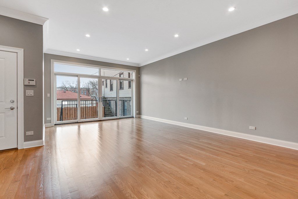 an empty living room with a sliding glass door to a balcony