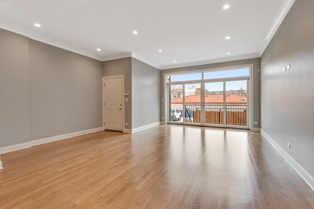 an empty living room with a large window and wooden floors