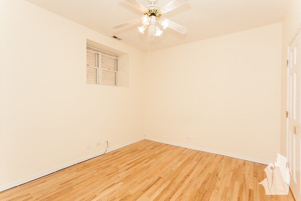 an empty room with wood floors and a ceiling fan