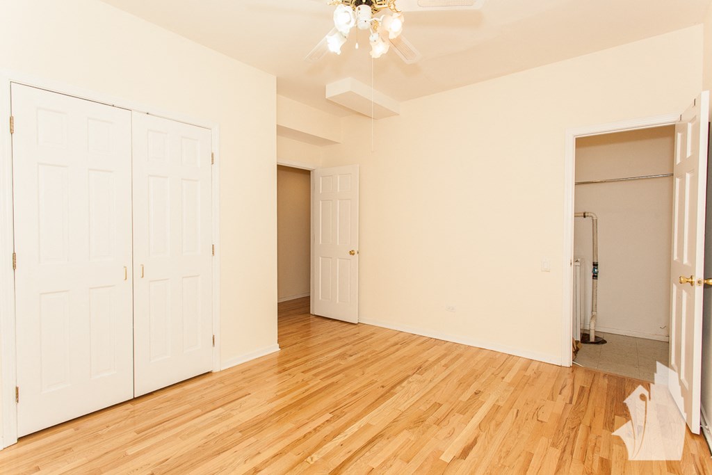 an empty living room with white doors and a wood floor