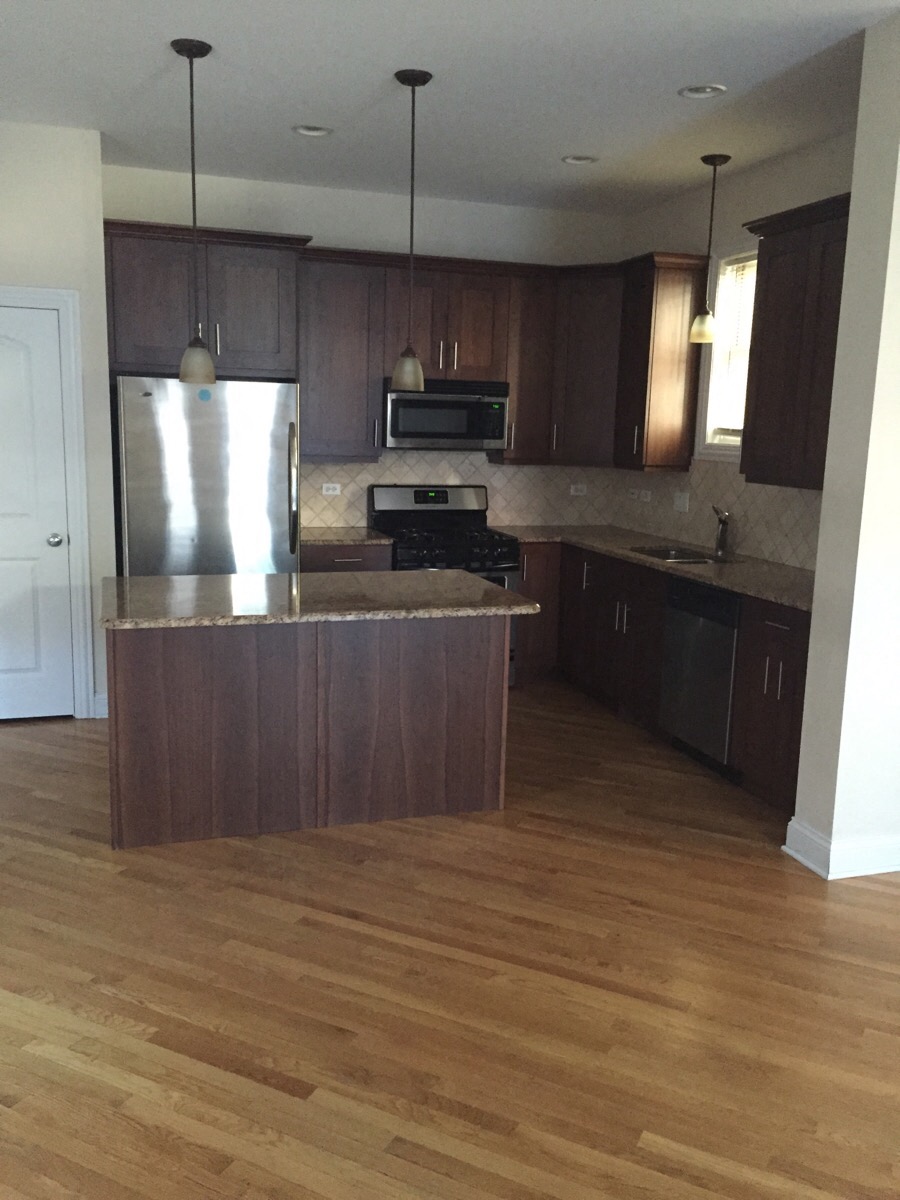 an empty kitchen with wooden floors and stainless steel appliances