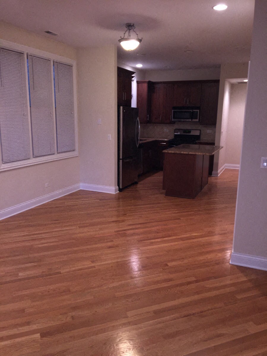 an empty living room and kitchen with wood floors