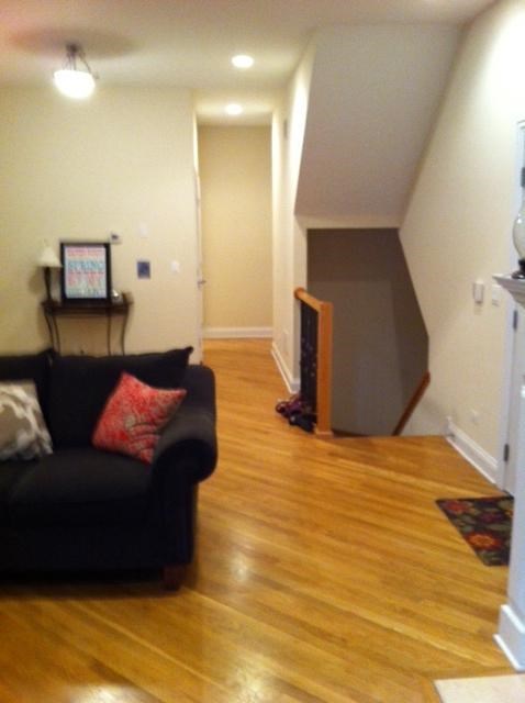 a living room with a black couch and a wooden floor