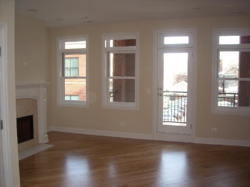 an empty living room with windows and a fireplace