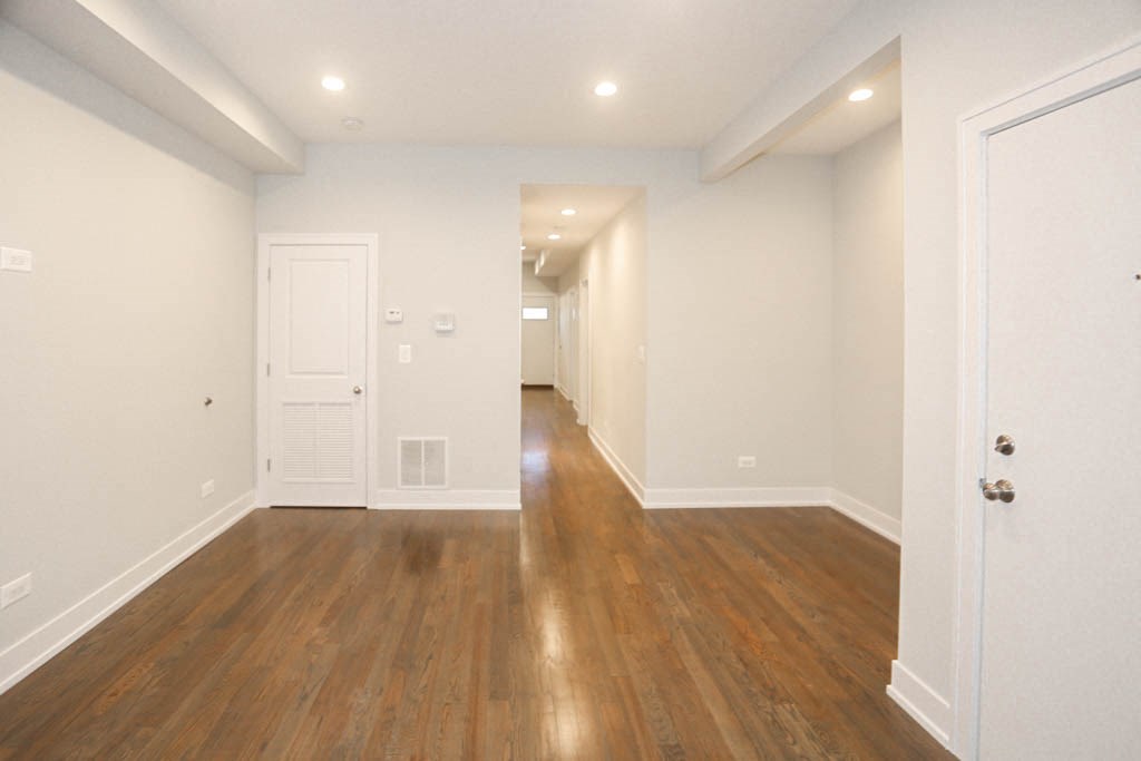 a renovated living room and hallway with wood floors and white walls