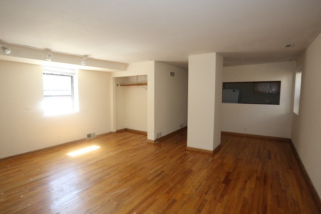 an empty living room with wood floors and a tv