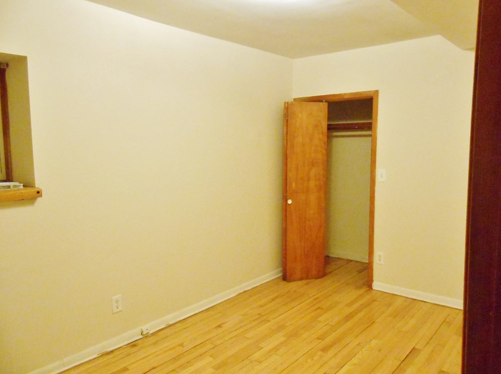 an empty room with a wooden floor and a door to a closet