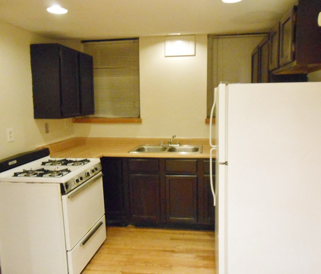 an empty kitchen with a stove refrigerator and sink