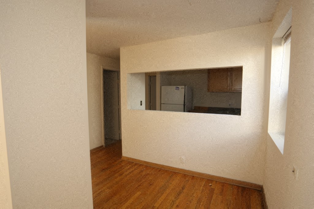 an empty living room and kitchen with a wood floor