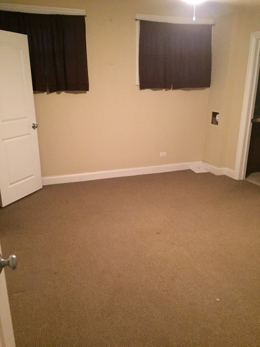 an empty room with a carpeted floor and two windows