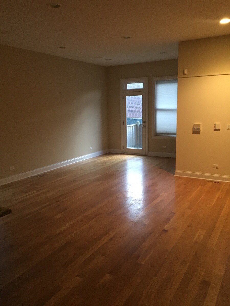 an empty living room with wooden floors and a door to a balcony