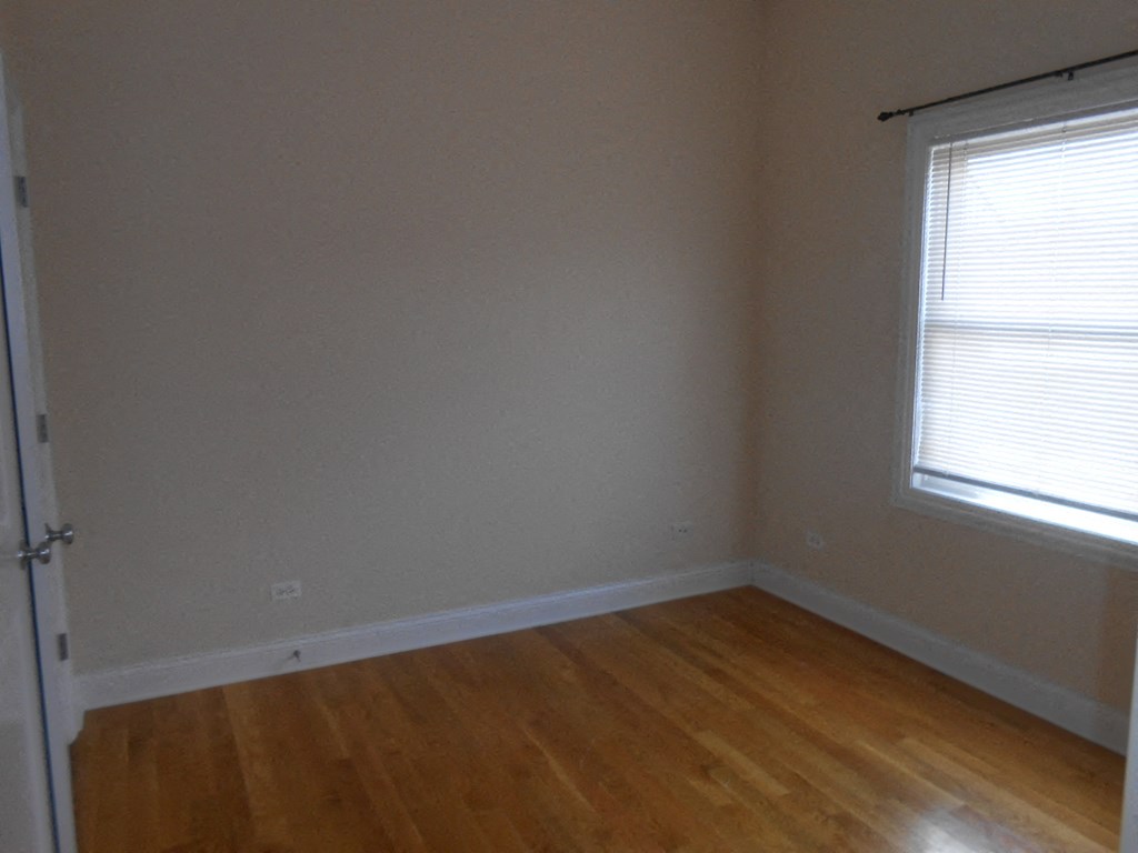 the corner of a room with wood floors and a window