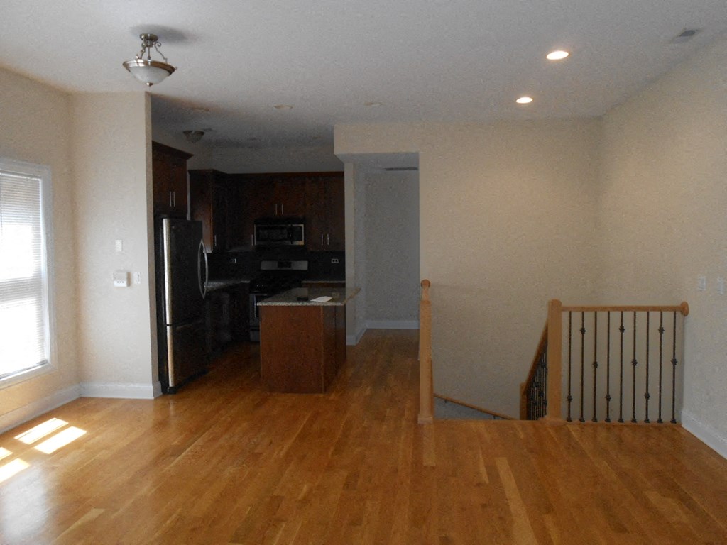 an empty kitchen and living room with a wooden staircase