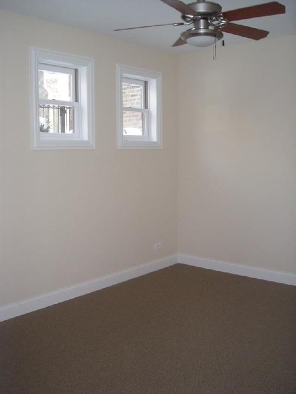 an empty room with a ceiling fan and two windows