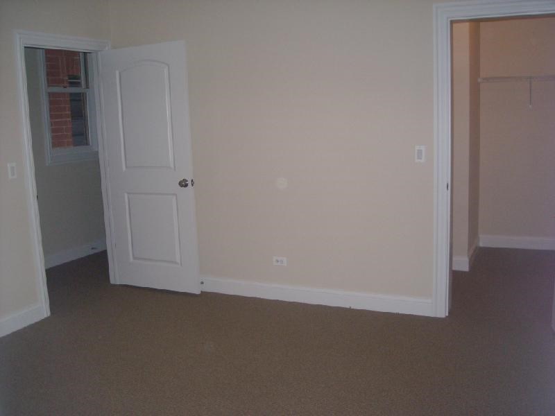 an empty room with a white door and a closet