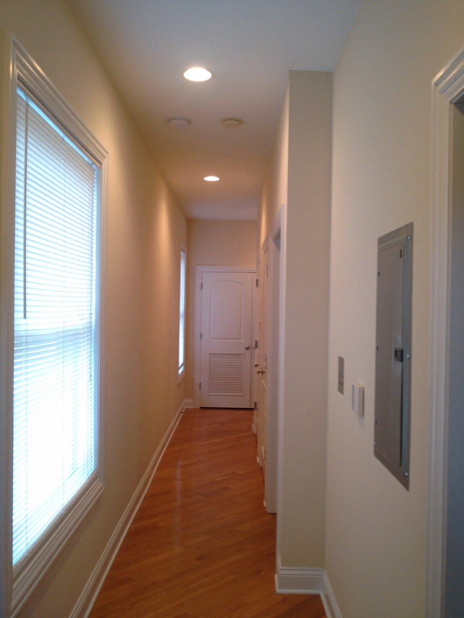 a hallway with white walls and wood floors and a white door