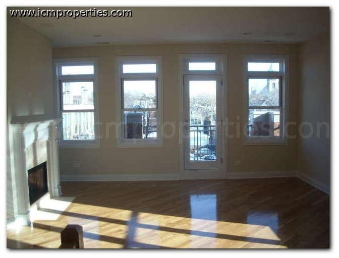 an empty living room with windows and a fireplace