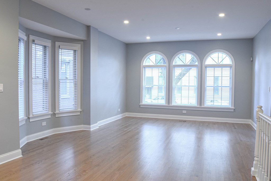 an empty living room with windows and a wooden floor