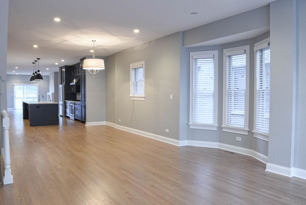 an empty living room with windows and a kitchen