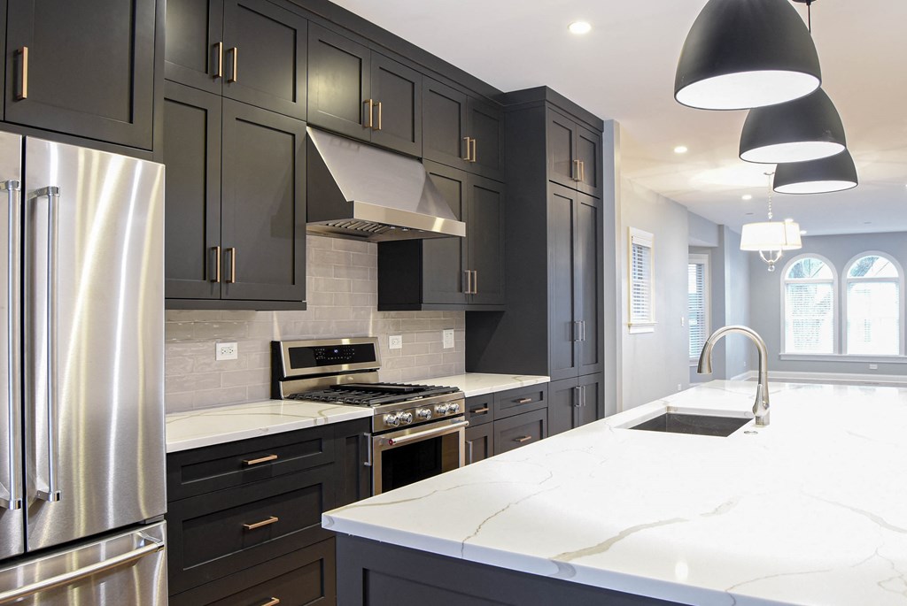 a large white kitchen with black cabinets and stainless steel appliances