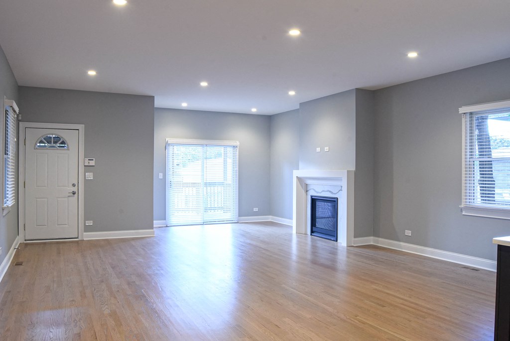 an empty living room with a fireplace and wooden floors