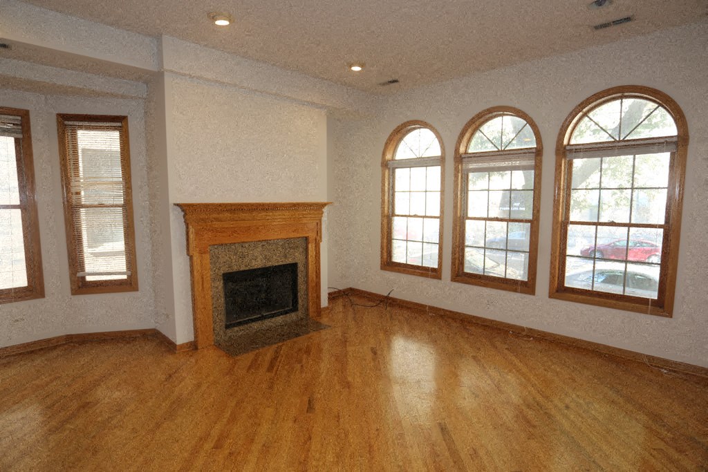 an empty living room with a fireplace and a wooden floor