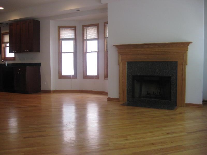 an empty living room with a fireplace and a wooden floor