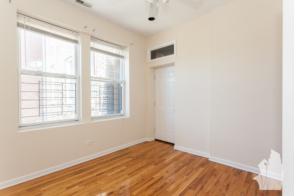 an empty room with wood flooring and two windows