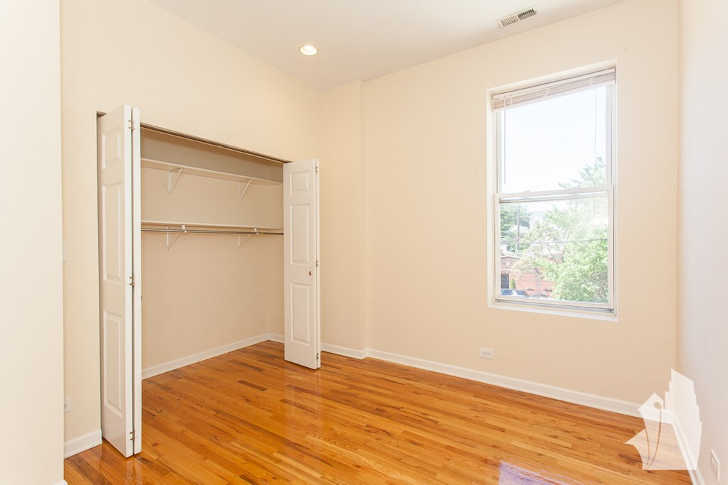 a bedroom with a wooden floor and a closet with a window