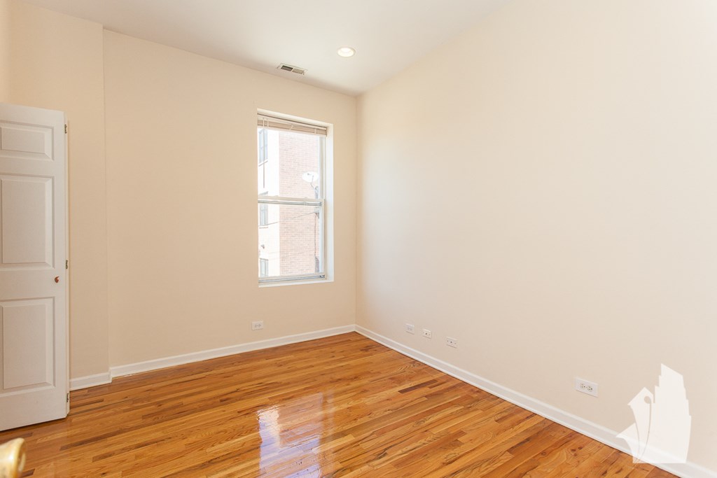 an empty living room with wood floors and a window