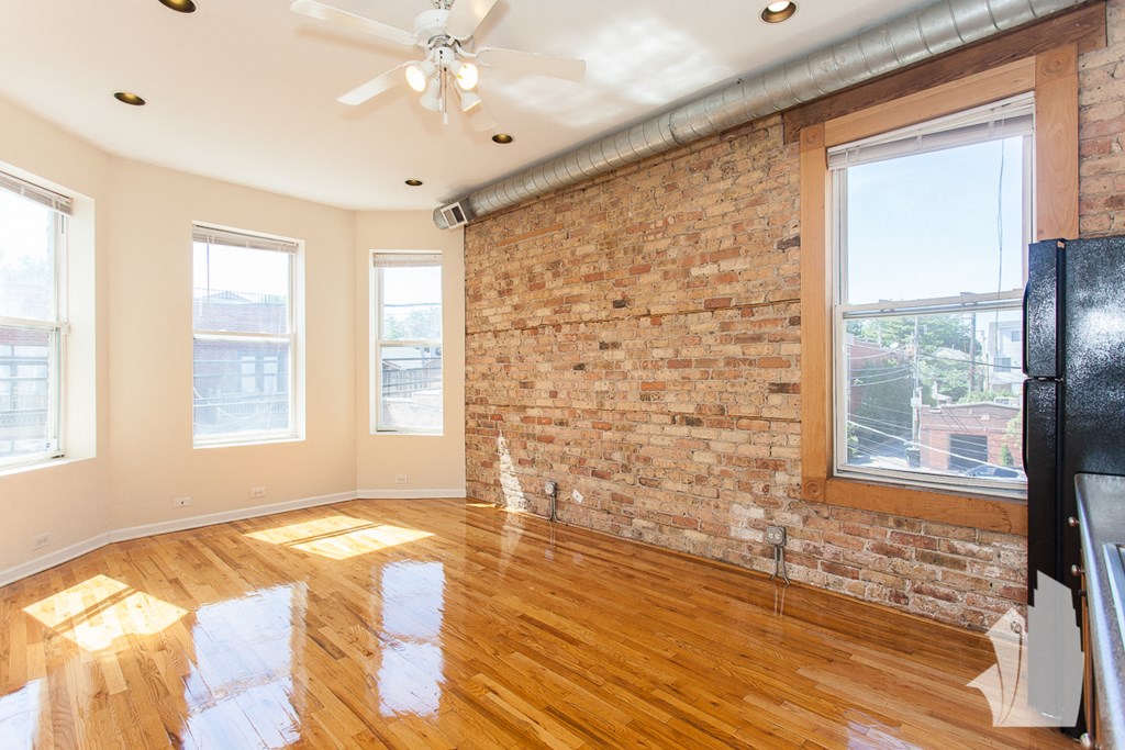 an empty living room with a brick wall and wood floors
