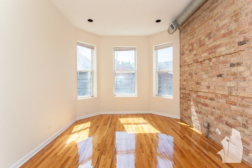 an empty living room with a brick wall and wood floors