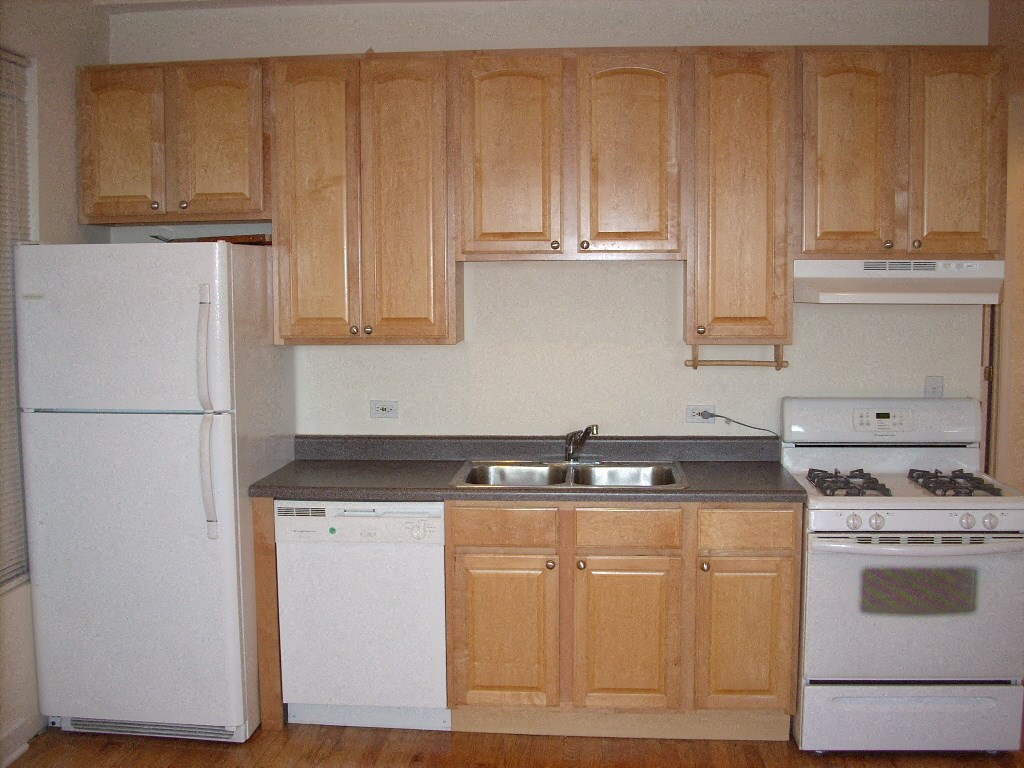 an empty kitchen with white appliances and wooden cabinets