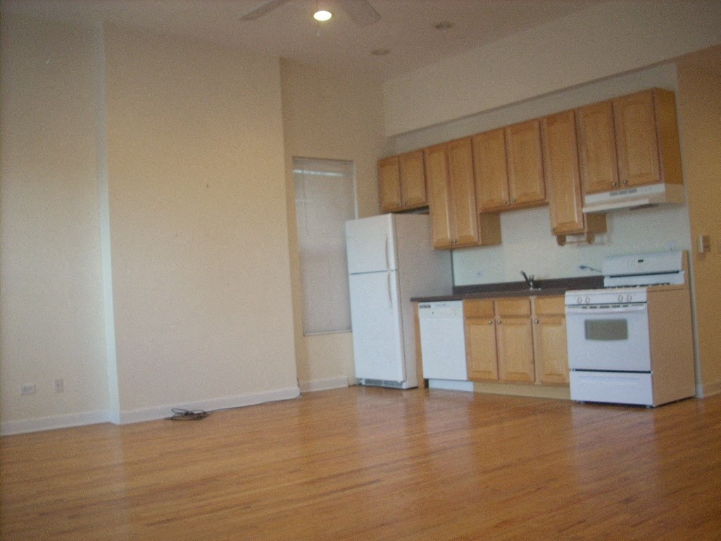 an empty kitchen with white appliances and wooden cabinets