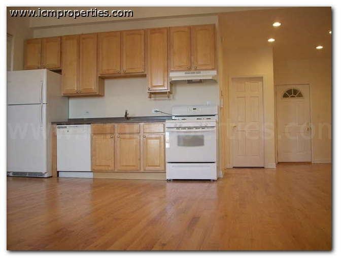 a kitchen with white appliances and wooden floors