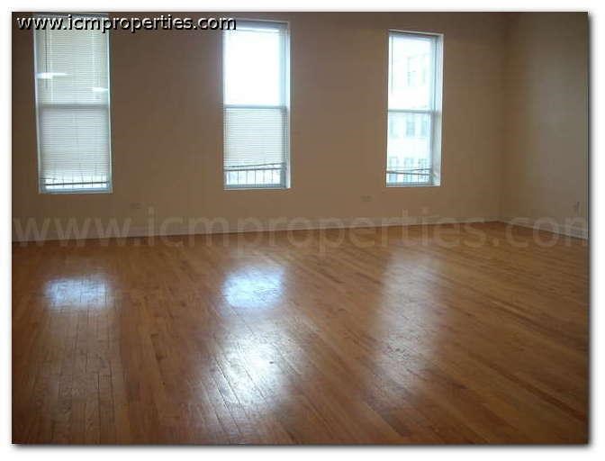 an empty living room with wooden floors and windows