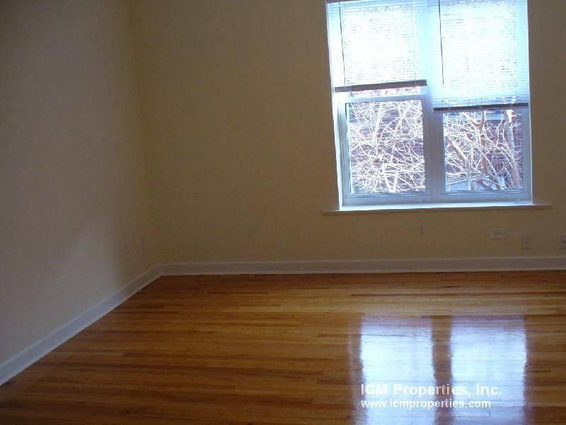 an empty room with a window and wooden floors