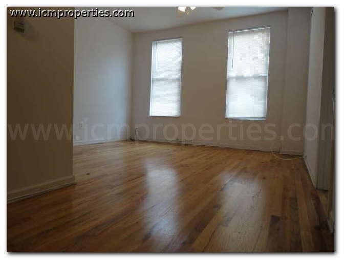 an empty living room with wood floors and two windows