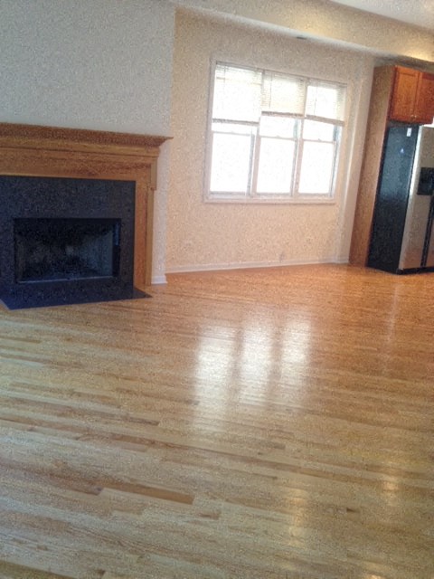 an empty living room with a fireplace and wooden floors