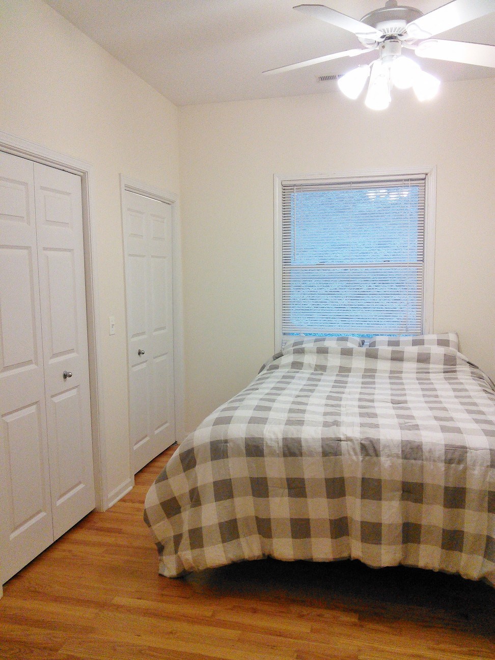 a bedroom with a bed and a window and a ceiling fan