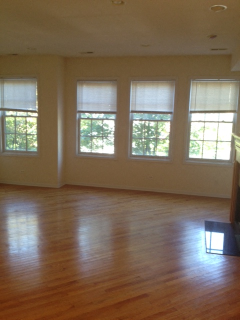 an empty living room with a hard wood floor and large windows