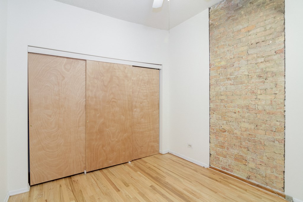 an empty room with wood floors and a brick wall and a wooden door