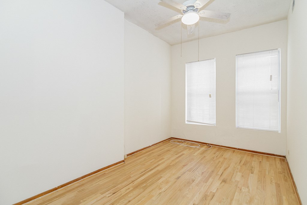 an empty room with wood floors and a ceiling fan